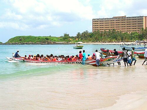 Visitors loaded into a Pirogue for a pleasure trip from Ngor to île de Ngor, a popular holiday spot for Dakar's locals. In the background is the Ngor Hotel, catering to Senegalese and business travelers to Dakar.