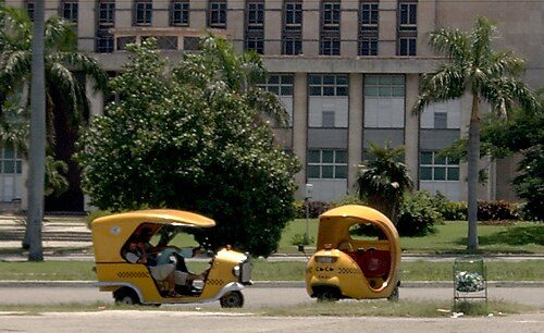"Cocotaxis" in Plaza de la Revolución, Havana. Because of the rapid growth of tourism in Cuba, taxi drivers can earn more than lawyers and doctors.