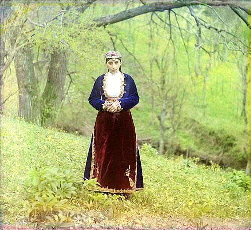 An Armenian woman in national costume poses on a hillside near Artvin, circa 1910.